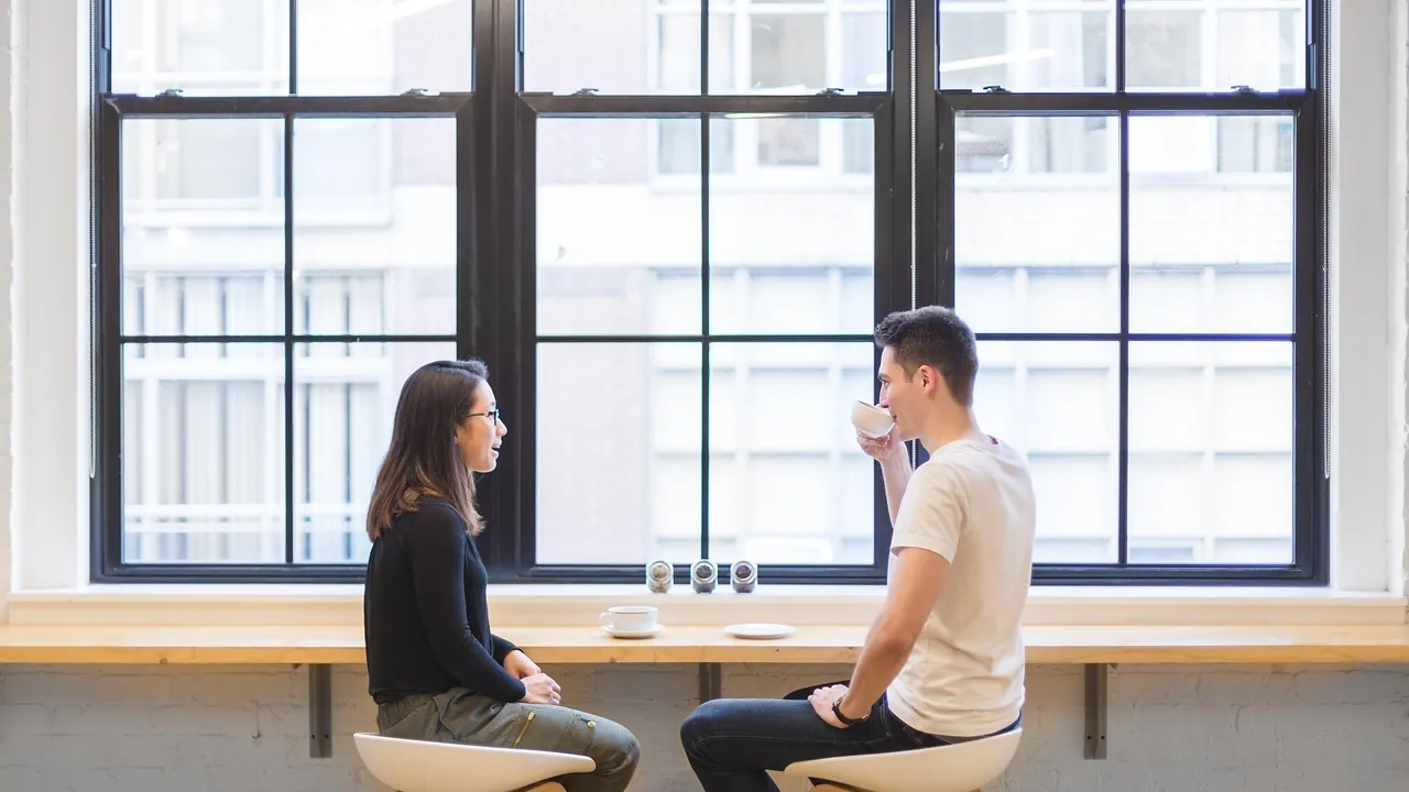 Un homme et une femme discutant calmement à une table près d'une grande fenêtre