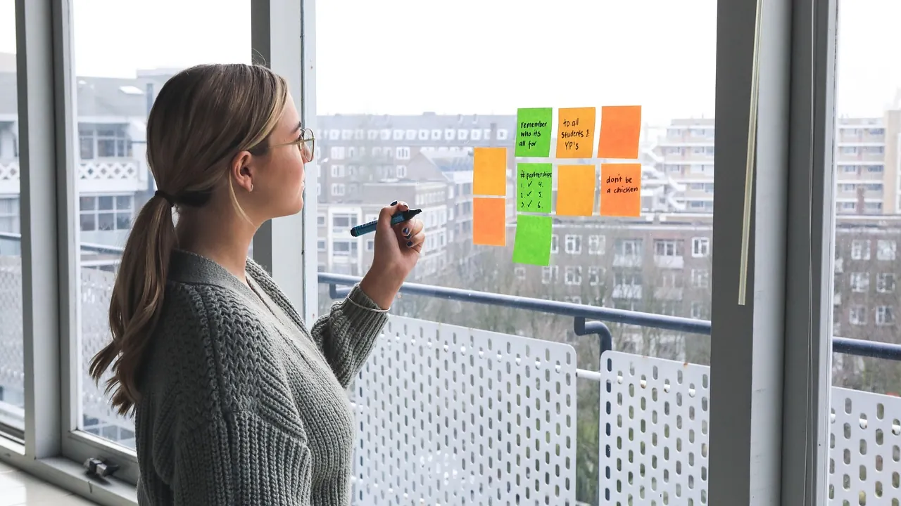 Femme présentant ses idées devant un mur de notes adhésives