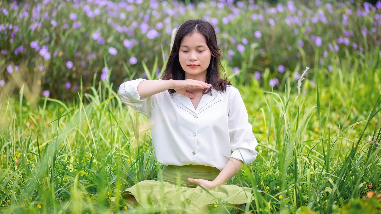 Femme pratiquant un exercice de respiration au milieu d'un champ de fleurs