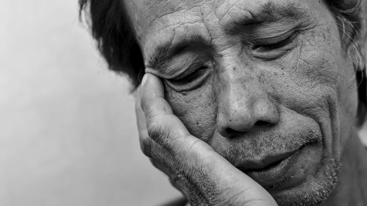 Homme fatigué, les yeux fermés, la joue dans la main, en noir et blanc