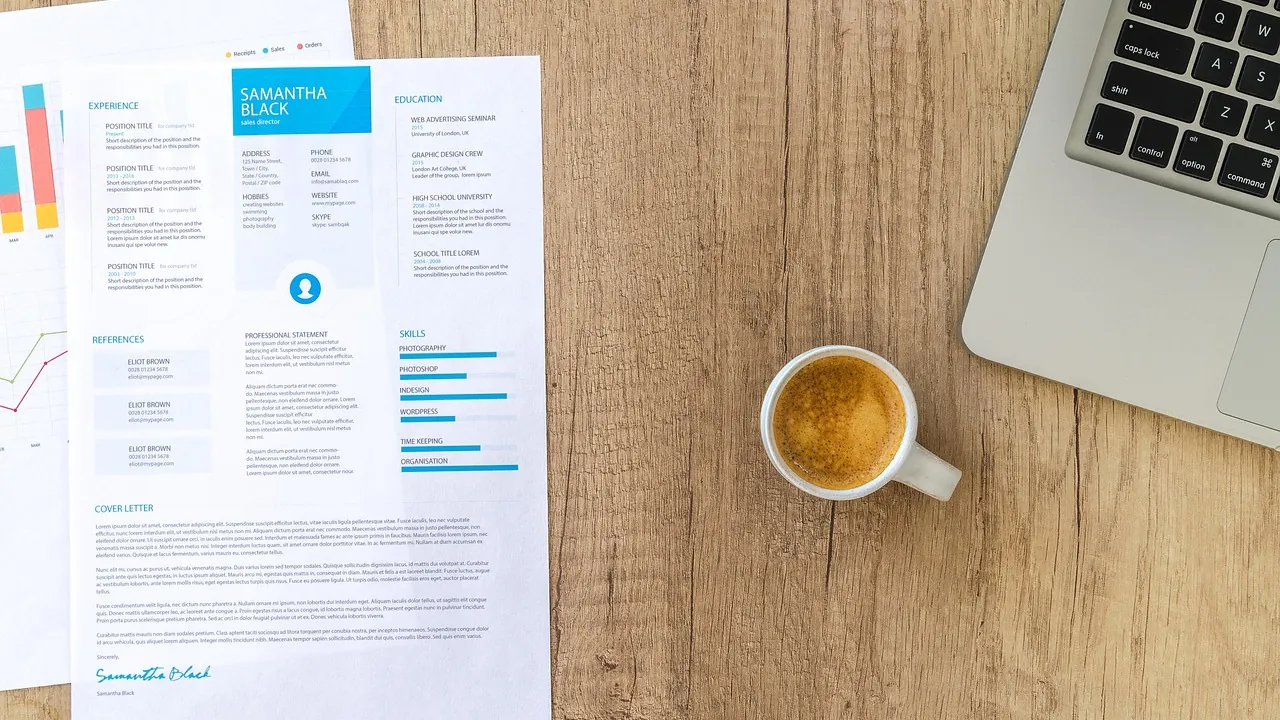 Curriculum vitae posés sur un bureau à côté d'une tasse de café et d'un ordinateur